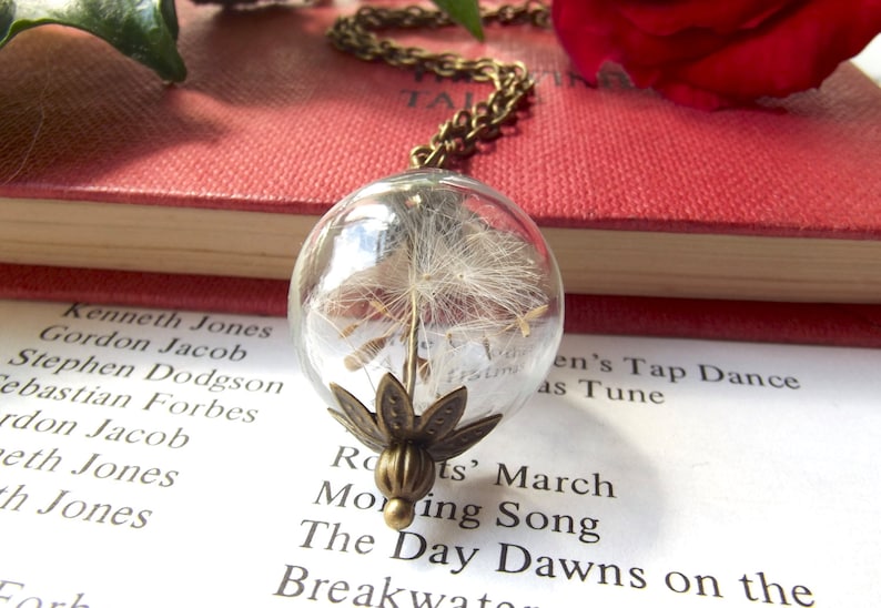 Real dandelion seeds inside a glass sphere strung from a long chain to create a striking necklace.