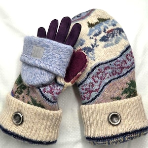 May include: A pair of convertible mittens with a patterned design. The mittens feature a light blue outer layer with a purple inner glove. The main mitten portion has a cream-colored base with a colorful pattern and a ribbed cuff with a silver button.