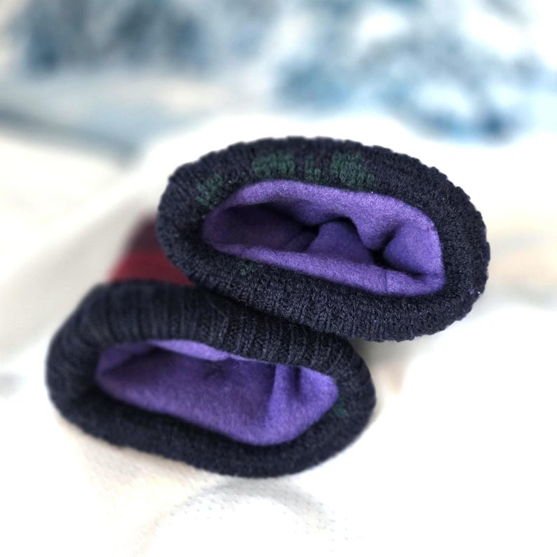 Puede incluir: Primer plano de dos guantes de punto azul marino con forro polar morado. Los pu&ntilde;os tienen un estampado de cuadros verdes y negros. Estos guantes est&aacute;n dise&ntilde;ados para mantener las manos calientes en climas fr&iacute;os.