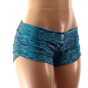 May include: Teal and blue ruched shorts with a textured, scale-like pattern. The shorts are made of a shiny, iridescent fabric. The garment is designed for dance or performance wear.
