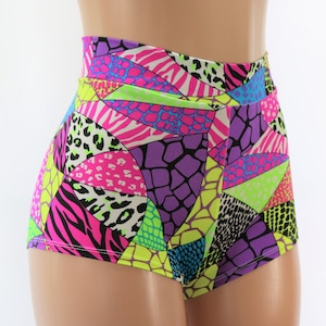 Puede incluir: Pantalones cortos de cintura alta con un estampado geométrico colorido que presenta patrones de animales como cebra, leopardo y piel de serpiente. El estampado es una mezcla de colores brillantes como rosa, verde, amarillo y azul.