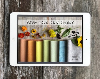 May include: A tablet screen displaying the text "Grow Your Own Colour" with a variety of colorful fabric swatches and dried flowers and seeds.