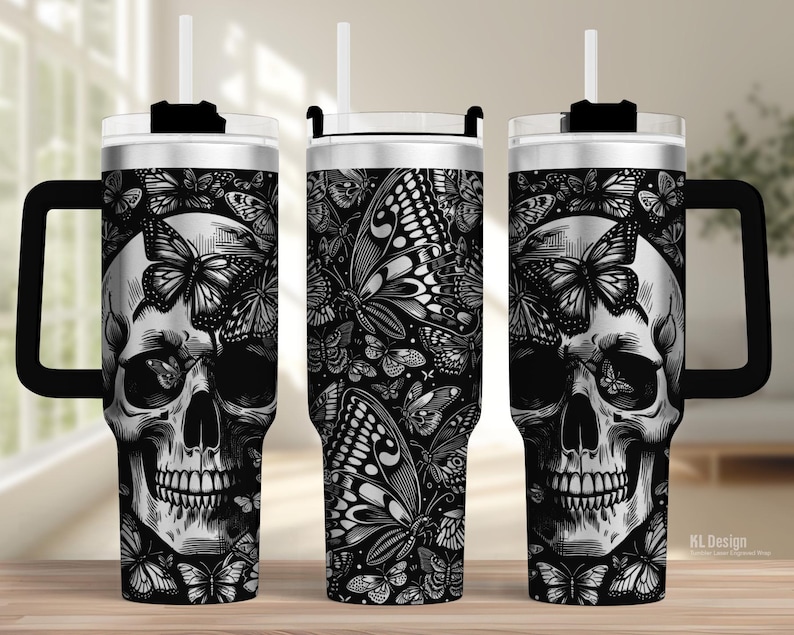 May include: A black and white tumbler featuring a skull design with butterflies. The tumbler has a black handle, a white straw, and a silver lid. The design is repeated on all sides of the tumbler.
