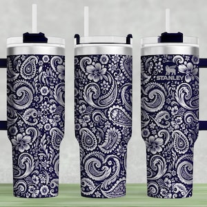 May include: A navy blue insulated tumbler with a white paisley floral design. The tumbler has a handle, a clear lid, and a white straw. The Stanley logo is visible on the side.