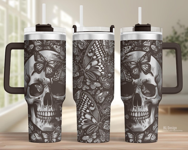 May include: A stainless steel tumbler with a black and white butterfly and skull design. The tumbler has a handle, a lid, and a straw. The design features a detailed skull surrounded by butterflies. The tumbler is suitable for cold and hot beverages.