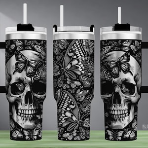 Könnte beinhalten: Ein schwarz-weißer Becher mit einem Totenkopf- und Schmetterlingsdesign. Der Becher hat einen schwarzen Griff, einen weißen Strohhalm und einen schwarzen Deckel. Das Design wiederholt sich auf allen Seiten des Bechers.