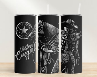 May include: A black and silver tumbler with a design of a woman in a cowboy hat riding a horse. The tumbler has the text "Wild West Since 197" and "Western Cowgirl" on it.
