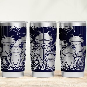 May include: Three stainless steel tumblers with a design of frogs under an umbrella. The frogs are in black and white with a blue background.