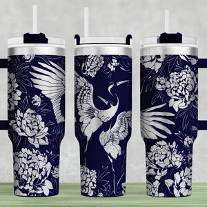 May include: A stainless steel tumbler with a navy blue background and a white floral pattern featuring cranes. The tumbler has a lid and a straw.