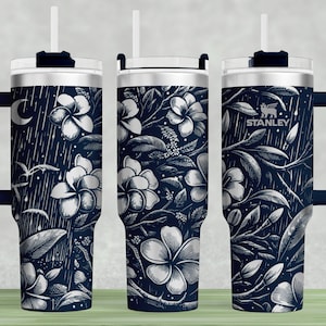 May include: A stainless steel travel mug with a navy blue floral pattern and a black handle. The mug has a straw lid and the word "STANLEY" is printed on the side.