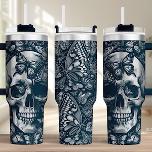 May include: A stainless steel tumbler with a dark blue handle and lid. The tumbler features a skull design with butterflies in a detailed black and white illustration. The tumbler includes a white straw.
