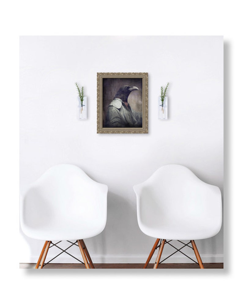 Puede incluir: Un retrato enmarcado de un cuervo con una camisa blanca y una corbata de lazo roja. El cuervo mira hacia la derecha. El retrato est&aacute; colgado en una pared blanca entre dos jarrones blancos con plantas verdes.