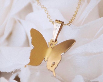 May include: A gold butterfly pendant necklace with a delicate chain. The pendant is a simple, elegant design.