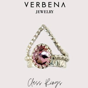 May include: A silver ring set with a pink gemstone and a beaded band. The ring has the number "02" engraved on it. Class Rings.