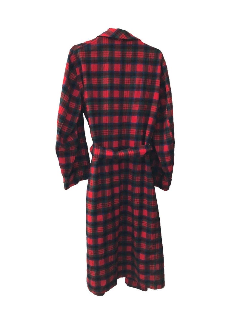 May include: A long-sleeved robe featuring a vibrant red and dark navy blue plaid pattern. The garment includes a matching fabric belt tied at the waist, a folded collar, and a straight hemline that extends to the lower calf area of the robe.