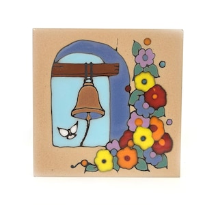May include: Square ceramic tile featuring a bell hanging in a blue arched window with a brown wooden beam. Colorful flowers in yellow, red, orange, and purple decorate the right side. The tile has a beige background.