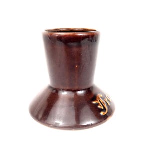 May include: A brown ceramic candlestick holder with a flared base and a narrower top. The candlestick holder has a glossy finish and a decorative design on the side.