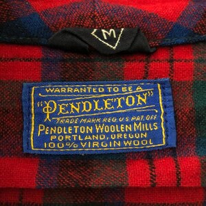 May include: A red and blue plaid shirt featuring a black size M tag and a blue rectangular label with yellow text reading Warranted to be a Pendleton, Pendleton Woolen Mills, Portland, Oregon, 100% Virgin Wool, Trade Mark Reg. U.S. Pat. Off.