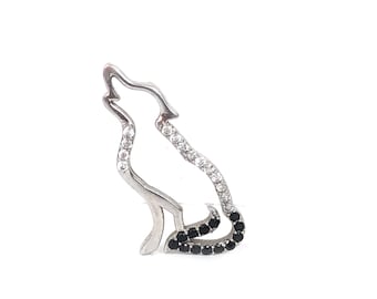 May include: A silver-colored pendant in the shape of a howling wolf. The wolf's outline is encrusted with clear and black gemstones. The pendant is set against a white background.