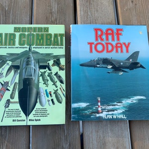 May include: Two hardcover books about military aircraft. The book on the left is titled "Modern Air Combat" and features a fighter jet with various missiles and bombs. The book on the right is titled "RAF Today" and shows a fighter jet flying over the ocean.
