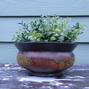 May include: A brown ceramic planter with a crackled glaze and gold accents. The planter is filled with green leafy plants.