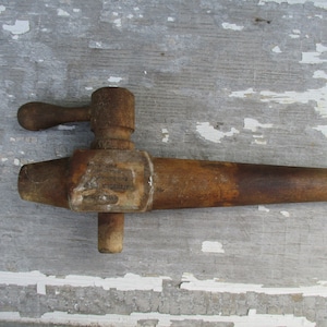 May include: A wooden spigot with a handle, showing signs of wear and age. The spigot is brown and has a label with faded text.