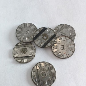 May include: Six silver metal tokens with black tape on the edges. Each token has a number and letters around the edge. The numbers are 6 and 9.