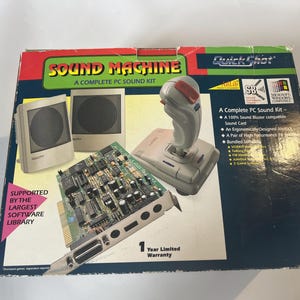 May include: A box for a Sound Machine PC sound kit. The box is blue, green, and white with the words "Sound Machine" and "Quick Shot" on it. The box includes a sound card, a joystick, and two speakers. The box also includes a one-year limited warranty.