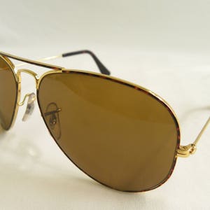 K&ouml;nnte beinhalten: Goldgerahmte Aviator-Sonnenbrille mit braunen Gl&auml;sern und einem Schildpattgestell.