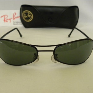 May include: Black Ray-Ban sunglasses with green lenses. The sunglasses are in a case.