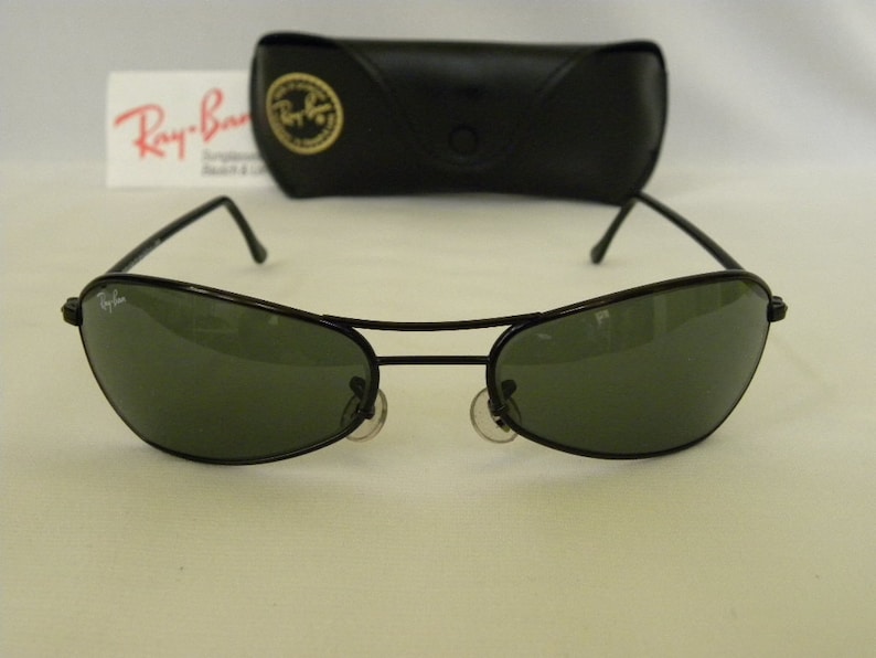 May include: Black Ray-Ban sunglasses with green lenses. The sunglasses are in a case.