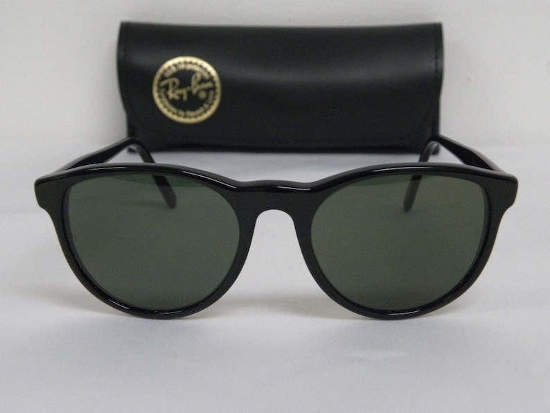 Puede incluir: Gafas de sol redondas negras con lentes verdes. Las gafas de sol est&aacute;n en una caja negra con el logotipo de Ray-Ban.