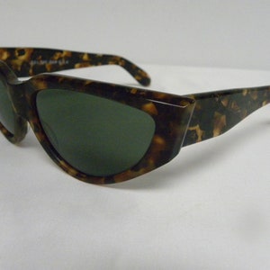K&ouml;nnte beinhalten: Schildkr&ouml;ten-Sonnenbrille mit dunkelgr&uuml;nen Gl&auml;sern. Die Sonnenbrille hat eine einzigartige, eckige Form.