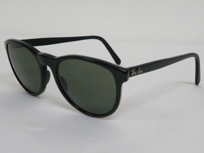 Puede incluir: Gafas de sol de pl&aacute;stico negro con lentes verdes y el logotipo de Ray-Ban en el lateral.