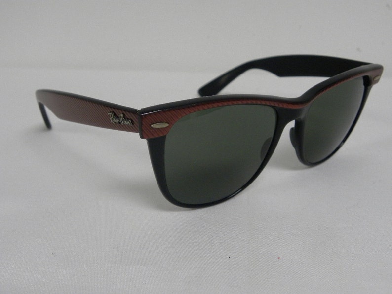 May include: Black sunglasses with red and black patterned frames. The sunglasses have dark lenses.