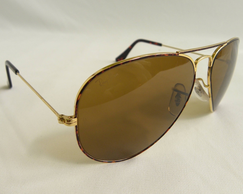 K&ouml;nnte beinhalten: Goldene Aviator-Sonnenbrille mit braunen Gl&auml;sern. Der Rahmen hat ein Schildpattmuster.