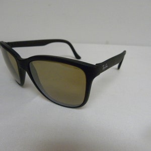 May include: Black plastic sunglasses with brown lenses. The sunglasses have a Ray-Ban logo on the side.
