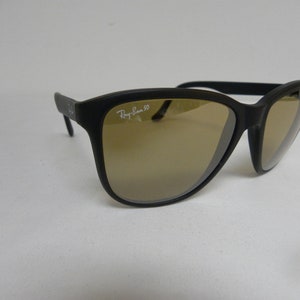 May include: Black Ray-Ban 50 sunglasses with brown lenses. The sunglasses have a rectangular frame with a slight curve at the top.