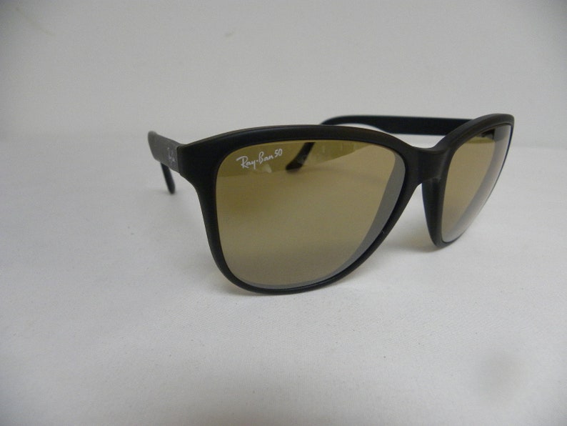 May include: Black Ray-Ban 50 sunglasses with brown lenses. The sunglasses have a rectangular frame with a slight curve at the top.