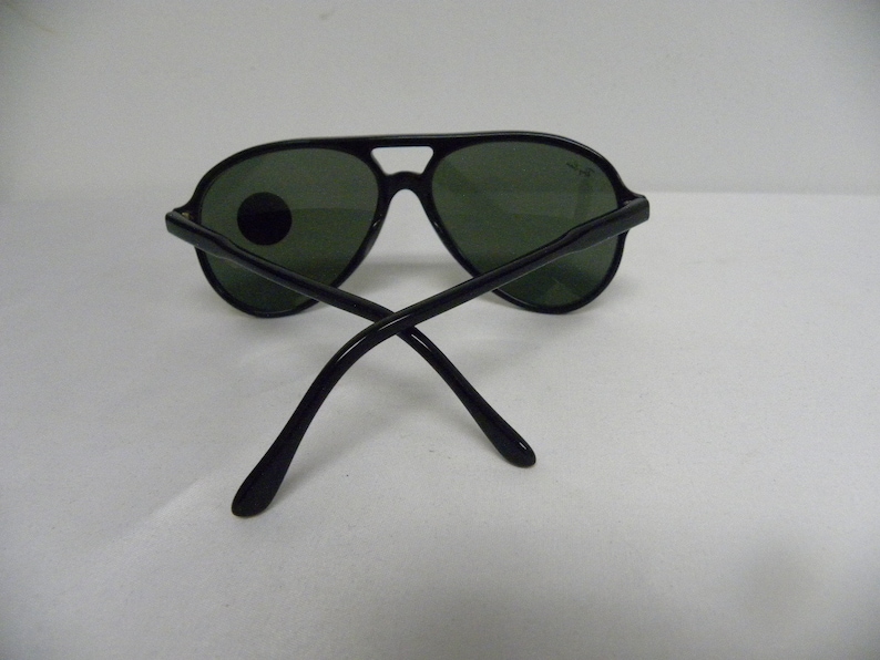 May include: Black aviator sunglasses with green lenses. The sunglasses have a metal frame and are in good condition.