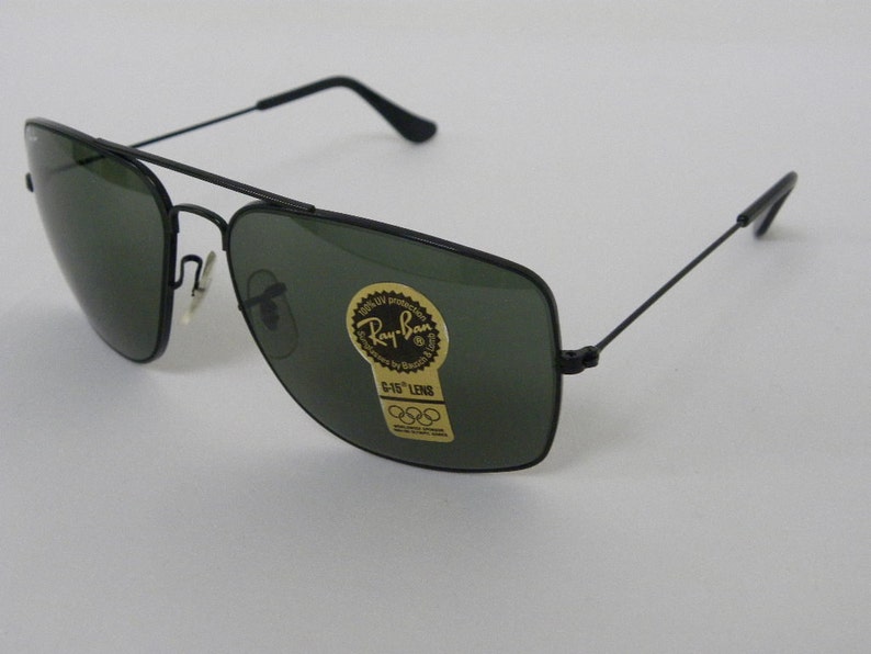 May include: Black Ray-Ban sunglasses with green lenses. The sunglasses have a gold sticker on the right lens that says "Ray-Ban" and "G-15 Lens".