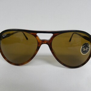 Puede incluir: Un par de gafas de sol aviador de carey marr&oacute;n con lentes marrones. Las gafas tienen el logotipo de Ray-Ban en la lente izquierda y una pegatina de Ray-Ban en la lente derecha.