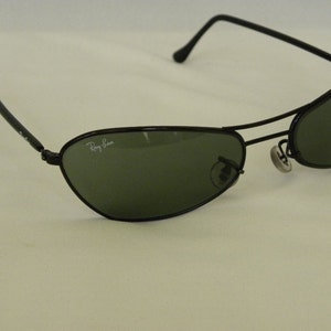 May include: Black Ray-Ban sunglasses with green lenses. The sunglasses have a metal frame and are in good condition.