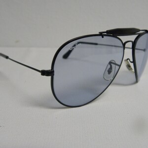 May include: Black aviator sunglasses with a silver nose bridge and Ray-Ban branding on the lens.