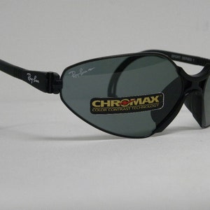 May include: Black Ray-Ban sunglasses with a gray lens and a black strap. The sunglasses have a label that says "CHROMAXX COLOR CONTRAST TECHNOLOGY" on the right lens.