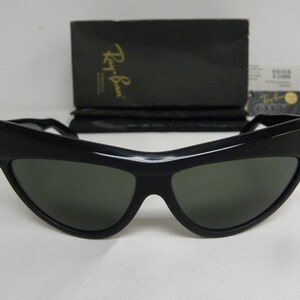 Puede incluir: Gafas de sol negras de ojo de gato con lentes verdes. Las gafas son de la marca Ray-Ban.