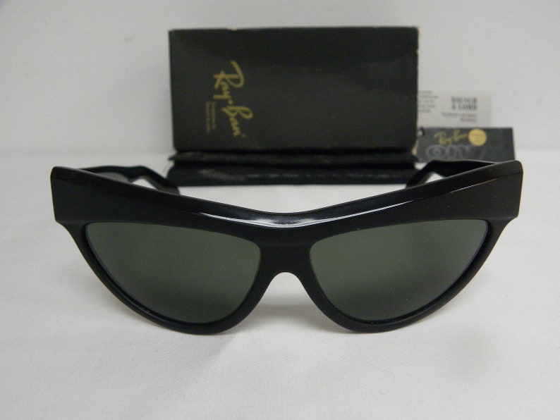 Puede incluir: Gafas de sol negras de ojo de gato con lentes verdes. Las gafas son de la marca Ray-Ban.