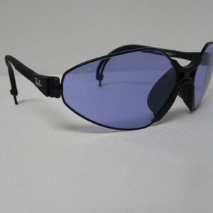 May include: Black wraparound sunglasses with a blue lens. The sunglasses have a flexible frame and a thin strap.