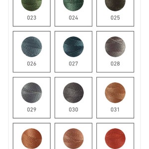 Op de afbeelding: Een set van 12 borduurgarenklossen in verschillende tinten groen, blauw, grijs en bruin. De klossen zijn gerangschikt in een rasterpatroon en gelabeld met de nummers 023 tot en met 034.