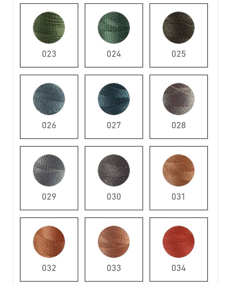 Op de afbeelding: Een set van 12 borduurgarenklossen in verschillende tinten groen, blauw, grijs en bruin. De klossen zijn gerangschikt in een rasterpatroon en gelabeld met de nummers 023 tot en met 034.
